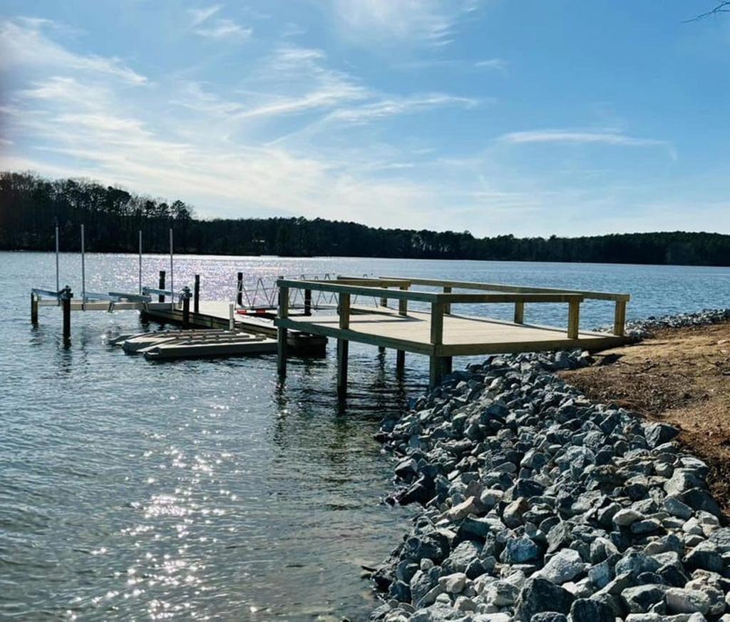 A dock in front of a nice and clean shoreline with a rock wall.