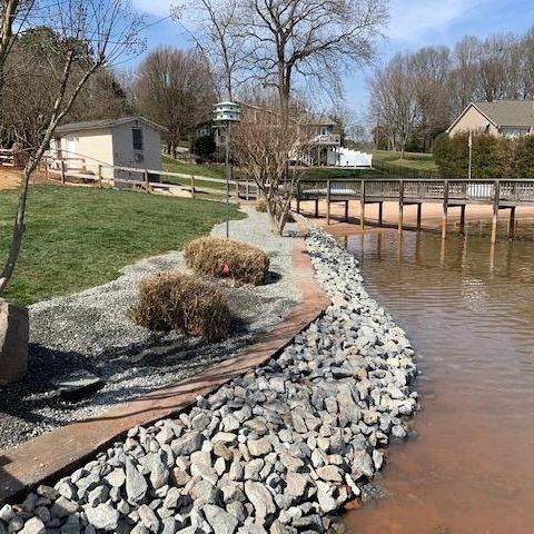 A very well placed and cleanly installed rock wall, bordering between the shoreline and a retention wall.